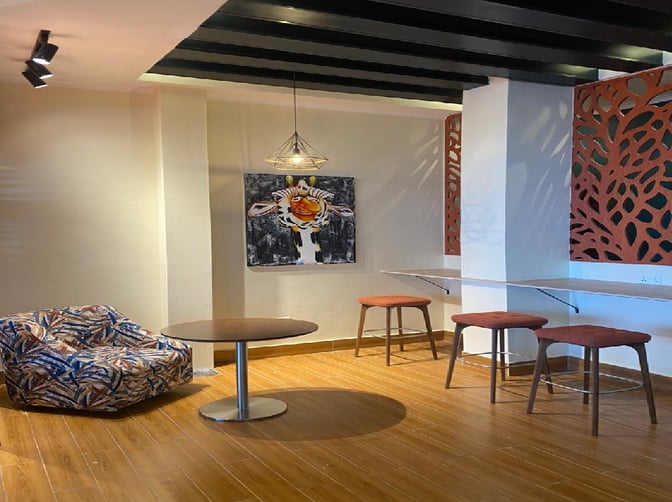 The Kilimeru Lounge at Arusha Airport features a seating area with a round table, cushioned chair, and bar stools for travelers.