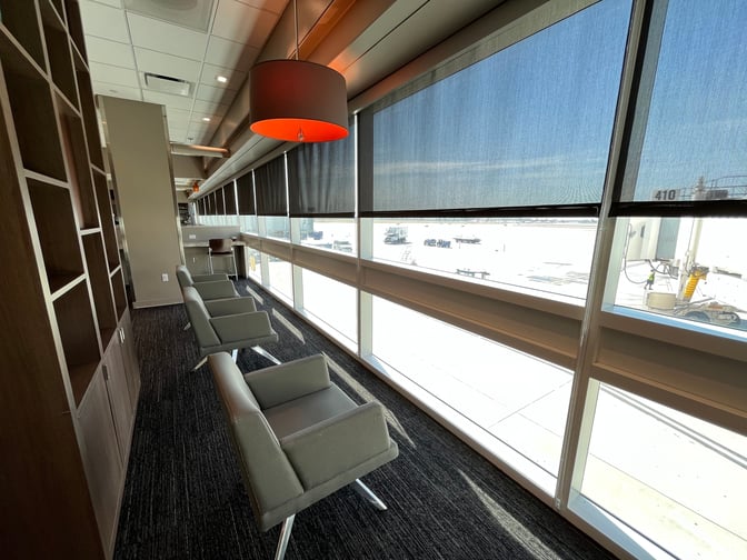 Seating area in the Aspire Lounge at Ontario International Airport features armchairs facing large windows with views of the tarmac.