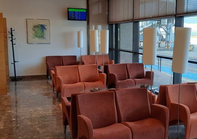 The seating area in the Picos de Europa Lounge at Asturias Airport features armchairs and tables with views of the tarmac.