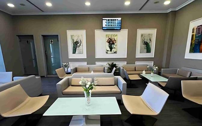 The seating area in Pearl Lounge at Aswan International Airport features comfortable chairs and tables, with decorative artwork on the walls.