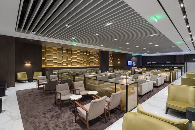 The seating area in Goldair Handling Lounge at Athens Airport features armchairs and small tables, providing a comfortable waiting space for travelers.