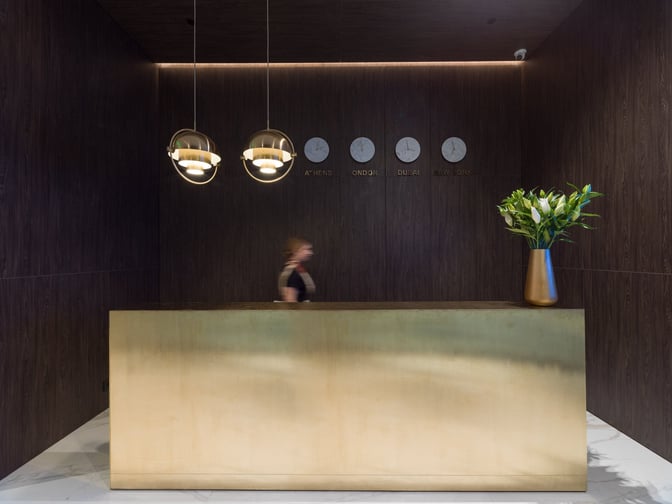 The reception area of Goldair Handling Lounge, Hall A at Athens International Airport, features a service desk and world clocks.