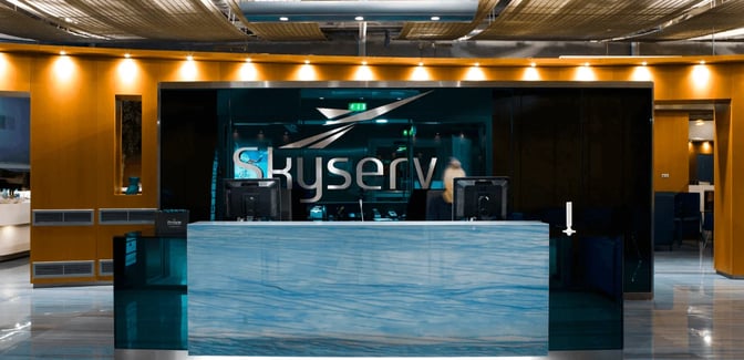The Skyserv Aristotle Onassis Lounge entrance at Athens International Airport features a reception desk with computer stations for guest check-in.