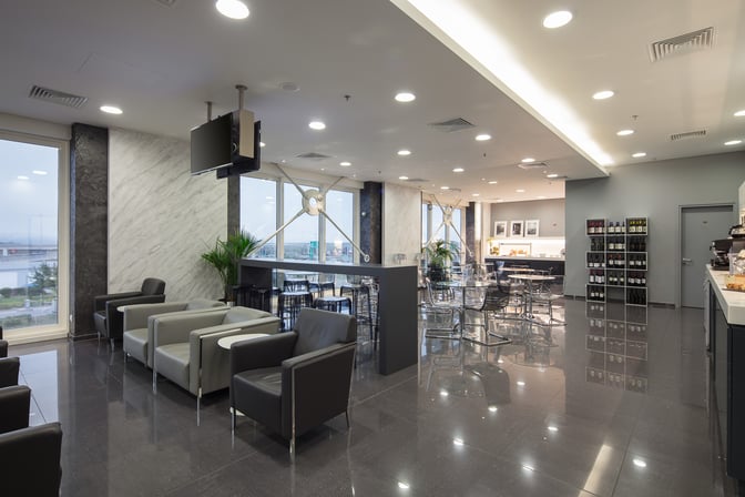 The Goldair Handling CIP Lounge at Athens International Airport features seating areas with armchairs, tables, and a self-serve food station.