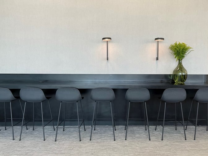 The seating area in the Goldair Handling x AIA Lounge features a long counter with bar stools and wall-mounted lighting.