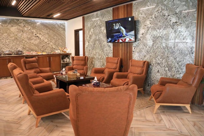 The Baghdad Lounge at Baghdad International Airport features comfortable seating around a central table, with a buffet area in the background.