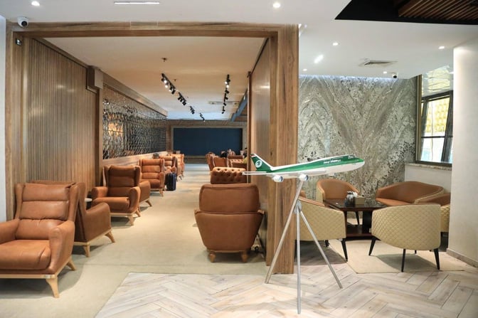The Baghdad Lounge at Baghdad International Airport features comfortable seating areas with armchairs and a model airplane display near the entrance.