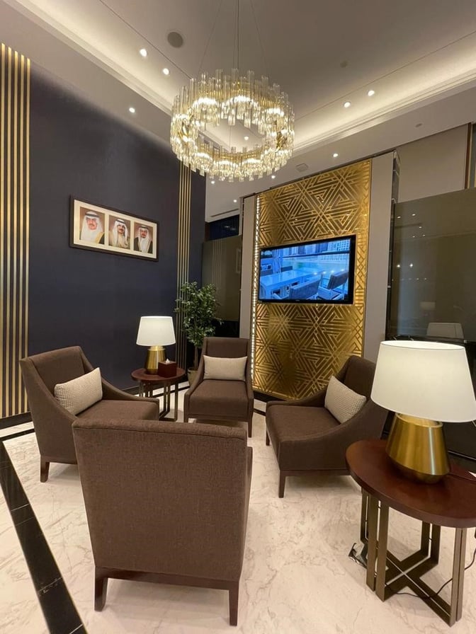 The Gulf Spa lounge at Bahrain International Airport features a seating area with armchairs, side tables, and a wall-mounted screen.