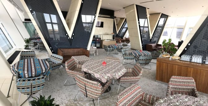 The Premium Bank Lounge at Heydar Aliyev International Airport features patterned seating and tables, with a refreshment area offering snacks and drinks.