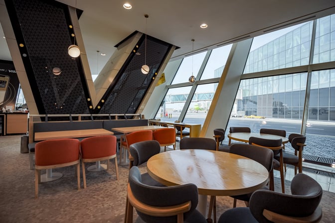 The seating area in the Premium Bank Lounge at Heydar Aliyev International Airport offers tables with views of the airport tarmac.