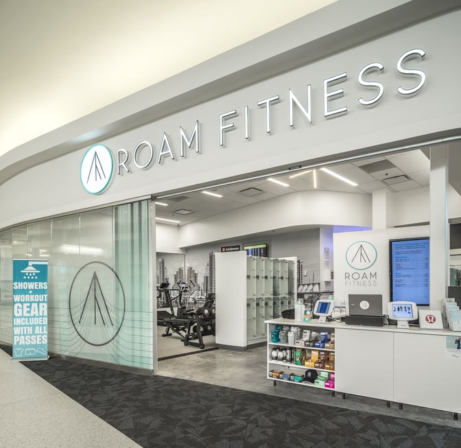 The entrance to ROAM Fitness at Baltimore-Washington International Airport features workout equipment, lockers, and a counter with fitness gear.