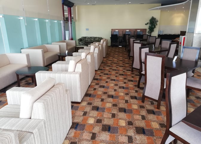 The Palm Strip Lounge at Bandaranaike International Airport features comfortable seating with armchairs and dining tables, providing a relaxing space for travelers.