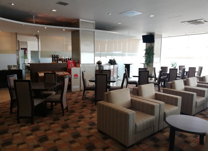 The Palm Strip Lounge at Bandaranaike International Airport features a seating area with armchairs, tables, and a self-serve beverage station.