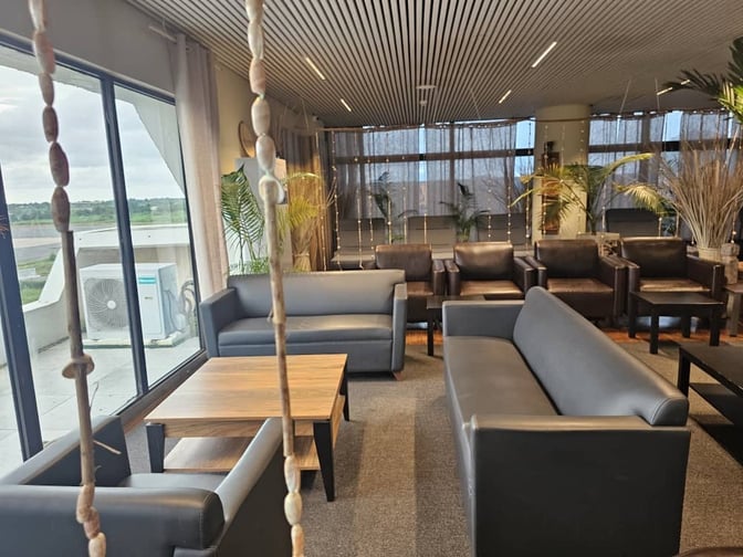The seating area in Banjul International Airport's First Class Lounge features sofas and armchairs with views of the runway.