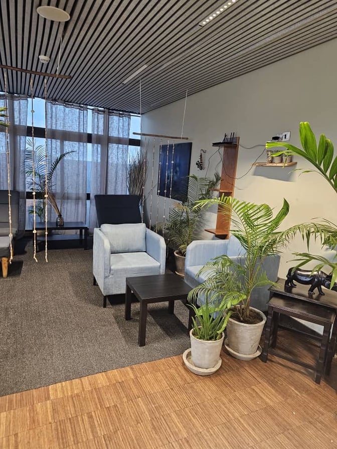 The seating area in Banjul International Airport's First Class Lounge features armchairs, a coffee table, and decorative plants for relaxation.