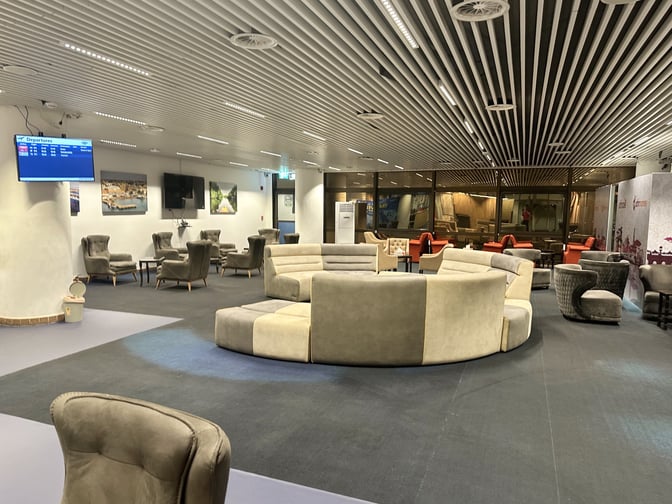 The Roumieh Business Lounge at Banjul International Airport features various seating arrangements with a departures screen for passenger convenience.