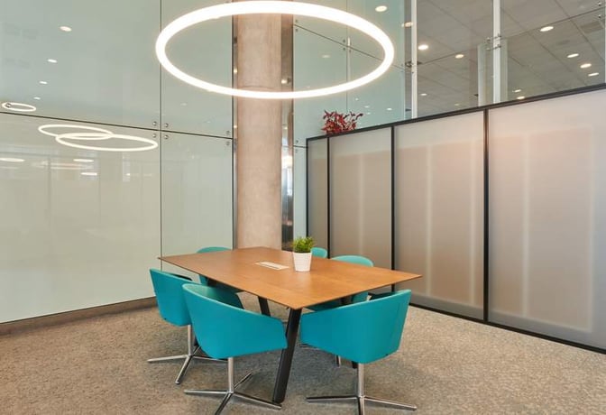 The Sala VIP Colomer at Barcelona Airport features a meeting area with a wooden table, swivel chairs, and a decorative plant.