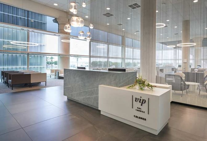 The Sala VIP Colomer at Barcelona Airport features a reception area with seating and large windows offering airport views.