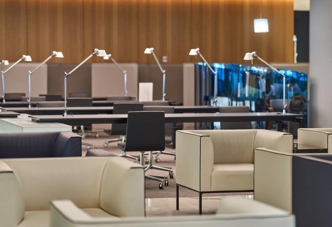 The Sala VIP Miró at Barcelona Airport features a seating area with armchairs and workstations equipped with desk lamps.