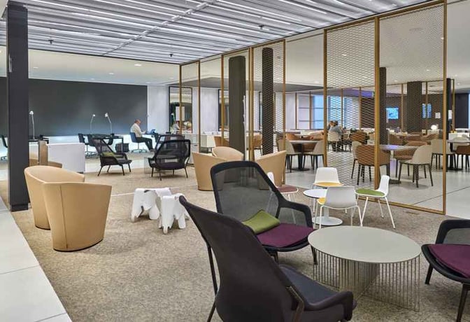 The Sala VIP Canudas at Barcelona Airport features a seating area with various chairs and tables for passenger relaxation.