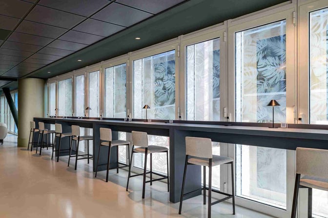 The work lounge at Bari Karol Wojtyła Airport features high counter seating with individual lamps, ideal for focused tasks.