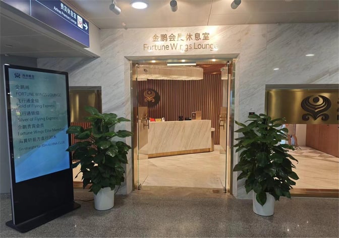 The entrance to the Fortune Wings Lounge at Beijing Capital International Airport features a reception desk and directional signage.