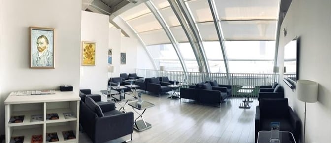 The seating area in the Airport Club Lounge at Beijing Capital International Airport features sofas and tables with large window views.