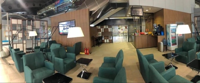 The CIP International Lounge at Beijing Capital International Airport features a seating area with armchairs and a self-serve refreshment station.