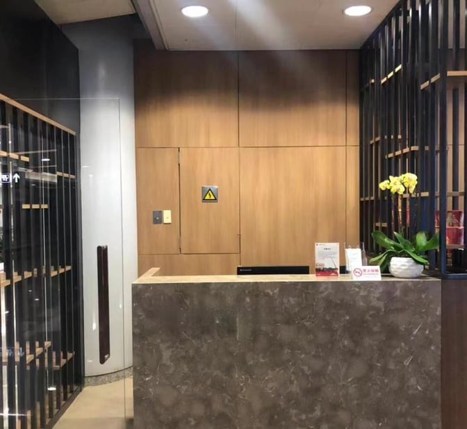 The reception desk at the CIP International Lounge in Beijing Capital International Airport features informational signage and a decorative plant.