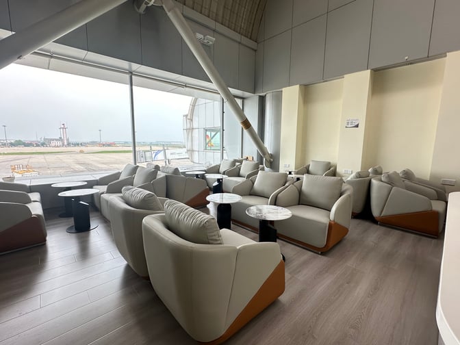 The CIPB2 Lounge at Beijing Capital International Airport features comfortable seating with tables, offering views of the airport tarmac.