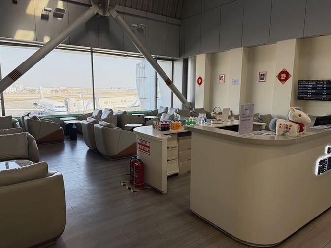The CIPB2 Lounge at Beijing Capital International Airport features a seating area with runway views and a counter offering beverages.