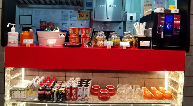 The Barcelo Lounge at Beijing Capital International Airport features a self-serve snack and beverage station with packaged noodles, nuts, and drinks.