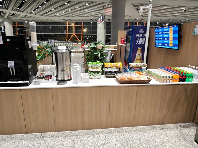 The CIP International Lounge at Beijing Capital International Airport offers a self-serve beverage and snack station with various drinks and packaged snacks.
