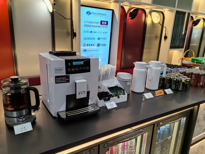 The beverage station in the Airport Club A2 Members Lounge at Beijing Capital International Airport offers coffee, tea, and assorted canned drinks.