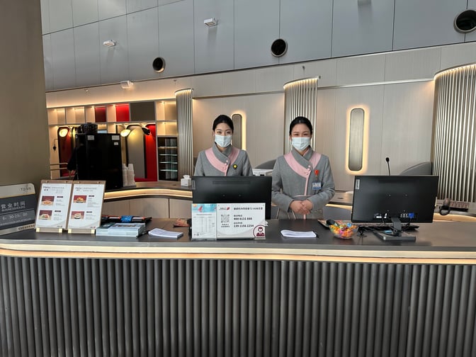 The reception area of the Airport Club A2 Members Lounge at Beijing Capital International Airport features staff ready to assist guests.