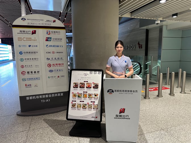 The Trvok A1 Lounge entrance at Beijing Capital International Airport features a reception desk and signage displaying partner logos and menu options.
