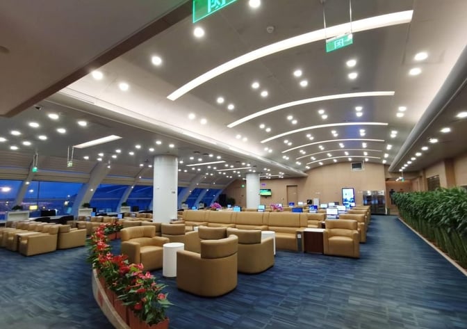 The China Eastern Lounge at Beijing Capital International Airport features spacious seating areas with armchairs and tables, offering views of the tarmac.