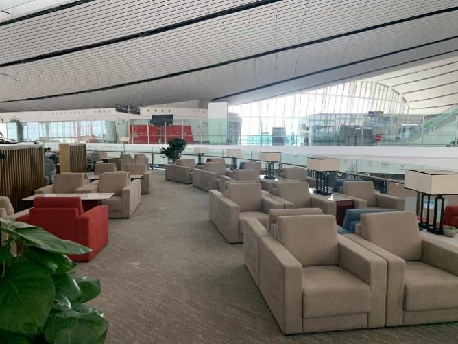 The seating area at BCS Domestic Premier Lounge in Beijing Daxing International Airport features comfortable armchairs with tables, offering airport views.