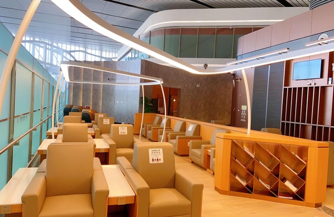 The seating area in China Southern's First/Business Class Lounge at Beijing Daxing Airport features armchairs with individual tables and power outlets.