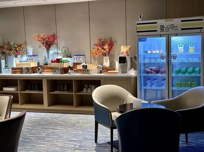 The CHUM Courtesy Lounge at Beijing Daxing International Airport features a self-serve snack area with beverages and seating.