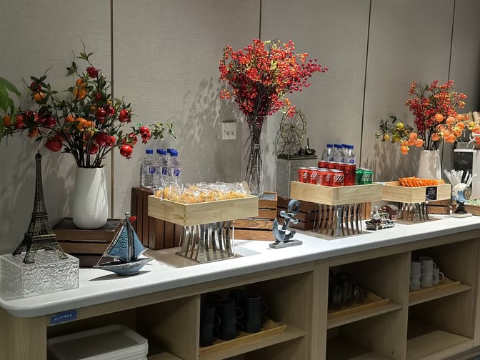 The CHUM Courtesy Lounge at Beijing Daxing International Airport features a self-serve snack station with packaged pastries, beverages, and decorative elements.