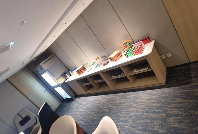 The CHUM Guest 79 Lounge at Beijing Daxing International Airport features a self-serve snack and beverage station with seating nearby.