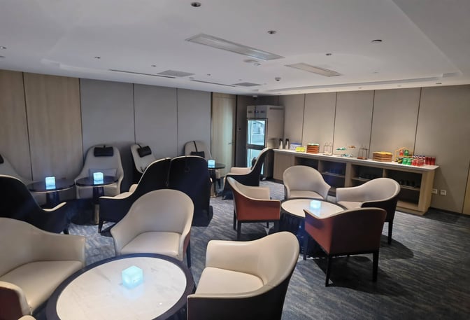 The CHUM Guest 79 Lounge at Beijing Daxing International Airport features seating areas with tables and a self-serve snack station.