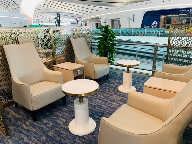 Seating area in CHUM International Lounge at Beijing Daxing Airport features comfortable chairs, small tables, and privacy screens near the concourse.