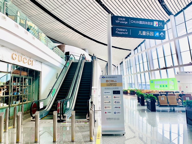 The CHUM VIP Lounge at Beijing Daxing International Airport is accessible via an escalator near a Gucci store and seating area.