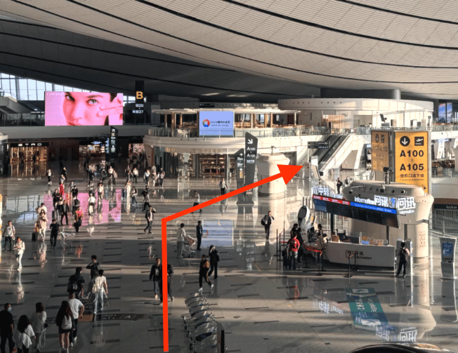 The CHUM VIP Lounge entrance at Beijing Daxing International Airport is located near escalators, adjacent to gates A100-A105.