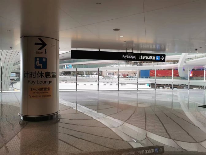 Signs direct travelers to the Pay Lounge at Beijing Daxing International Airport, located 50 meters away with 24-hour service.