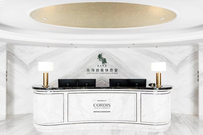 The reception desk at Dong Hai Passenger Lounge in Beijing Daxing International Airport features multiple computer stations and decorative lamps.