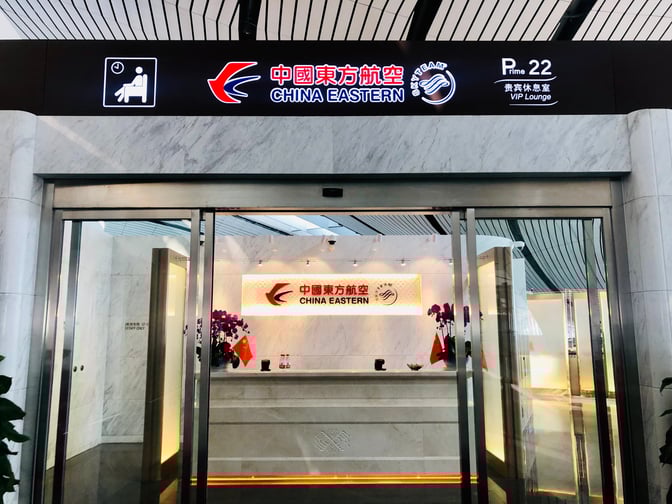 The entrance to China Eastern Airlines V5 Lounge at Beijing Daxing International Airport features sliding glass doors and a reception area.