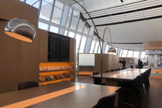 The V3 China Eastern Lounge at Beijing Daxing International Airport features communal tables, seating, and a display with flight information and reading materials.